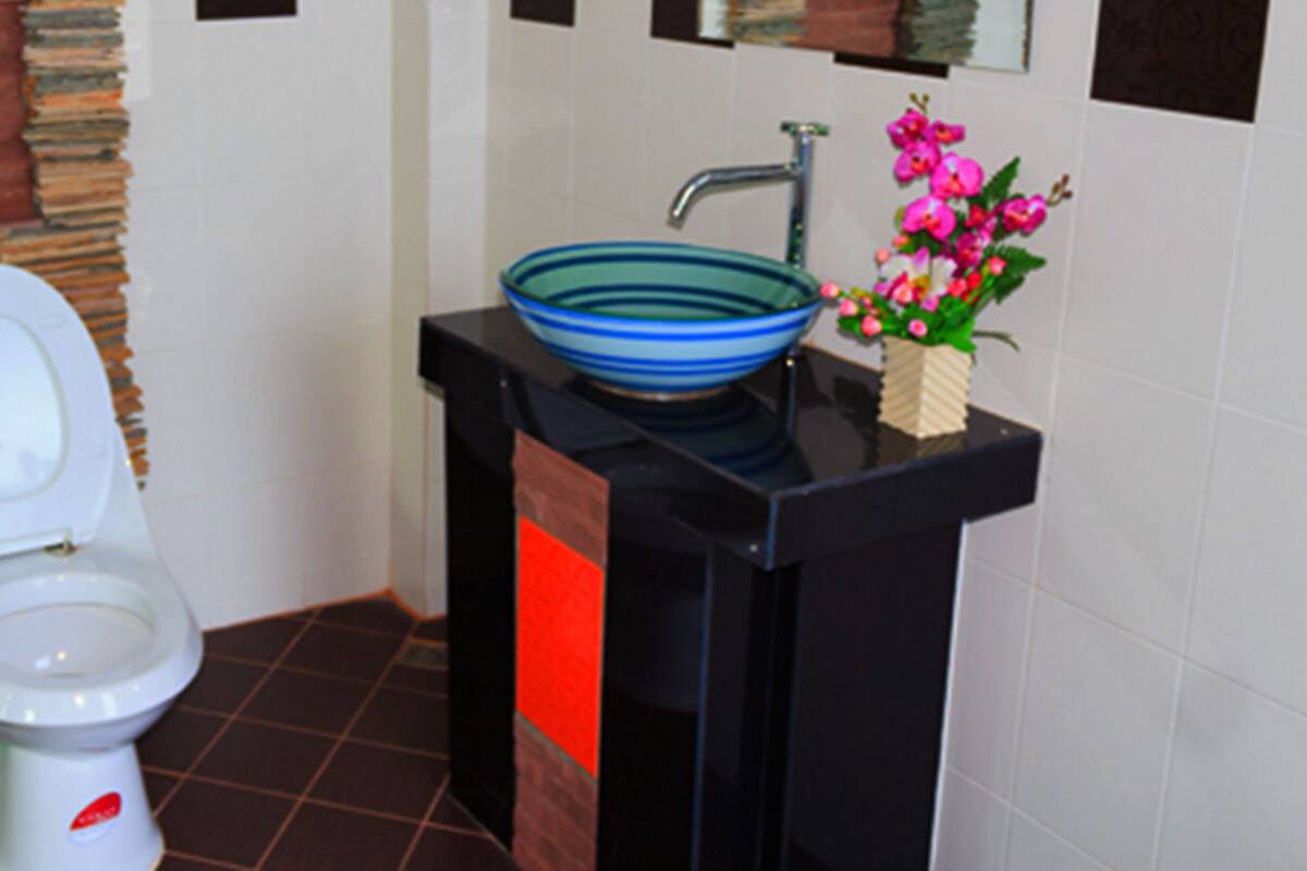 Un baño con un inodoro blanco, un lavabo azul y un cubo verde.