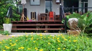 A covered outdoor area with a wooden deck, a white umbrella, and a potted plant.
