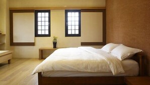 A bedroom with a bed, two windows, a bedside table, and a small plant. - Stay Resort (Fenglin)