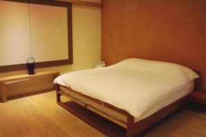 Un lit simple avec un cadre en bois et une literie blanche, dans une pièce dotée d’un plancher en bois et d’un mur d’accent de couleur marron.