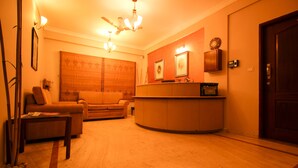 A living room with a sofa, a coffee table, and a reception desk. - Citadel by New Crescent (Bengaluru)