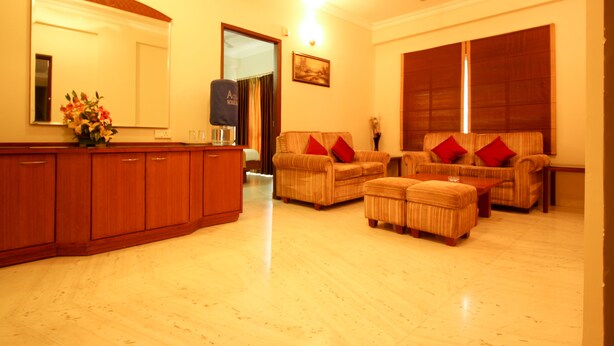 A living room with a wooden cabinet, two sofas with red cushions, and a ceiling fan. - Citadel by New Crescent (Bengaluru)