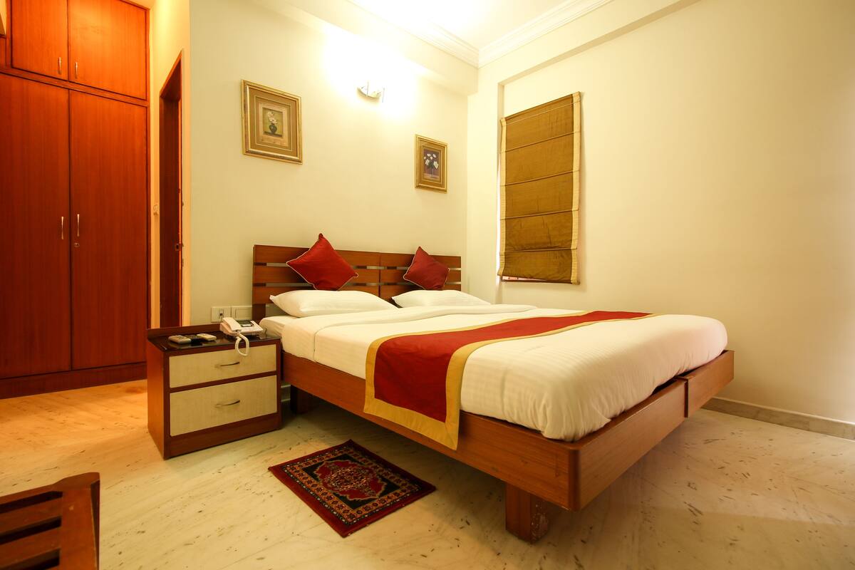 A bedroom with a wooden bed, a nightstand, a telephone, and a red patterned rug.