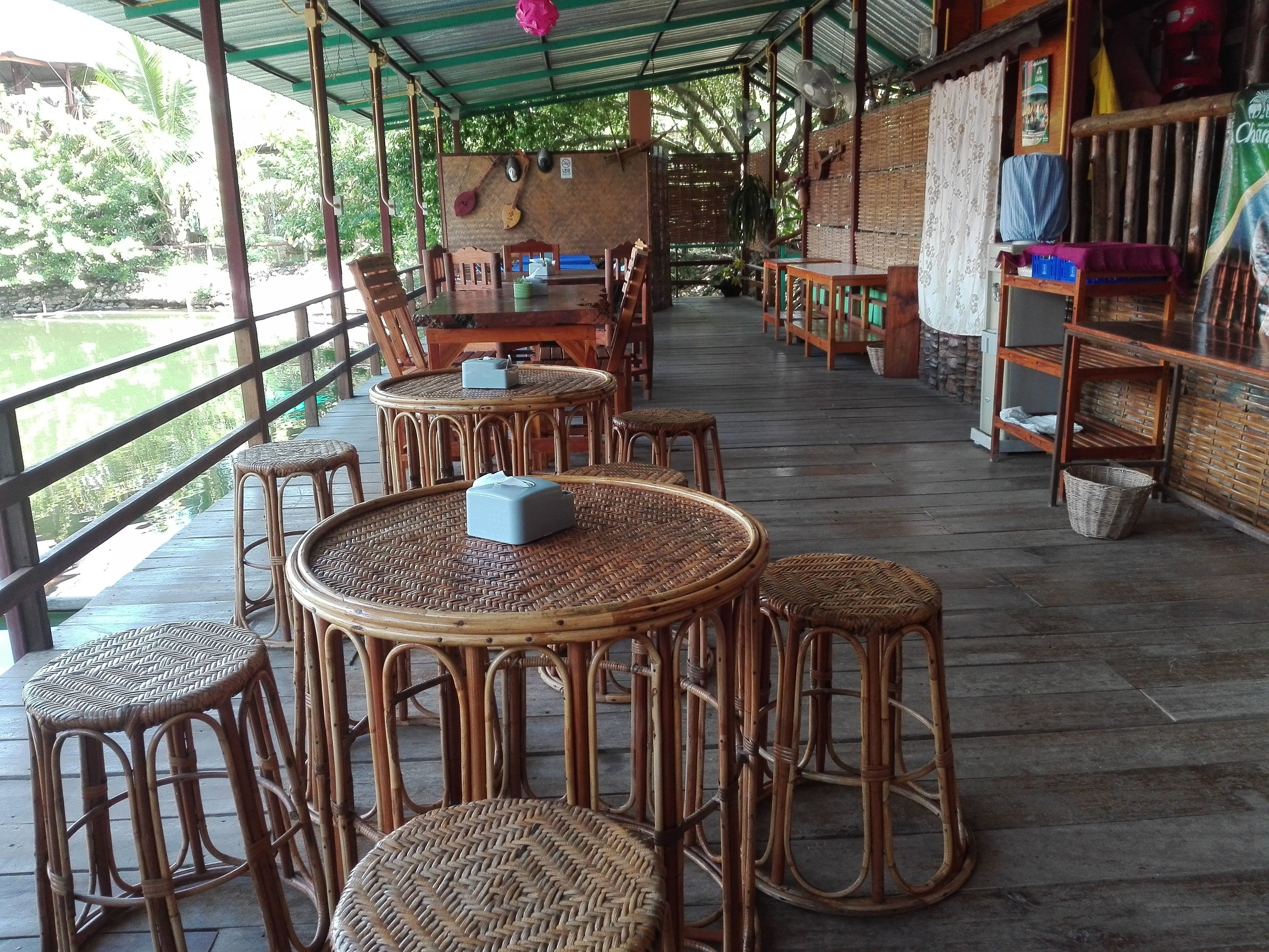 A covered outdoor seating area with wicker furniture and a view of a body of water.