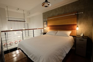 A modern bedroom with a large bed, wooden headboard, bedside tables, and a wall-mounted clock. - Eton Residences by StayHome Asia (Makati)