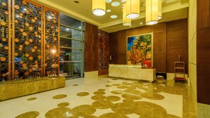 A lobby with a reception desk, a decorative wall with circular patterns, and a floor with circular designs. - Eton Residences by StayHome Asia (Makati)