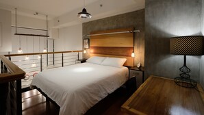 A modern bedroom with a large bed, wooden headboard, bedside lamps, and a wooden nightstand. - Eton Residences by StayHome Asia (Makati)