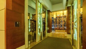A modern hotel lobby with a marble floor, wooden paneling, and glass elevator doors. - Eton Residences by StayHome Asia (Makati)