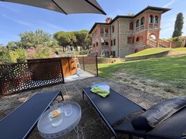 Un patio con dos sillones, una mesita con una jofaina y vasos, y una cerca decorativa.