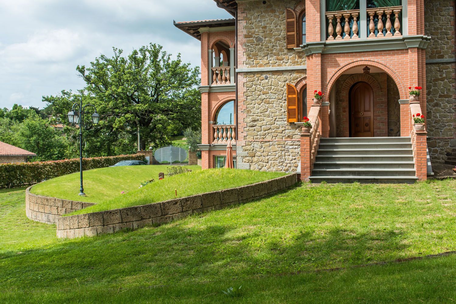 A stone and brick building with a grand entrance, a well-maintained lawn, and a satellite dish.
