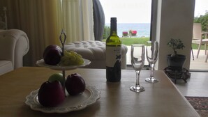 Una mesa de comedor con una botella de vino, dos copas y fruta en un plato decorativo.