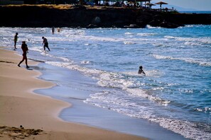Une plage où l’on voit des gens se promener et jouer dans l’eau.