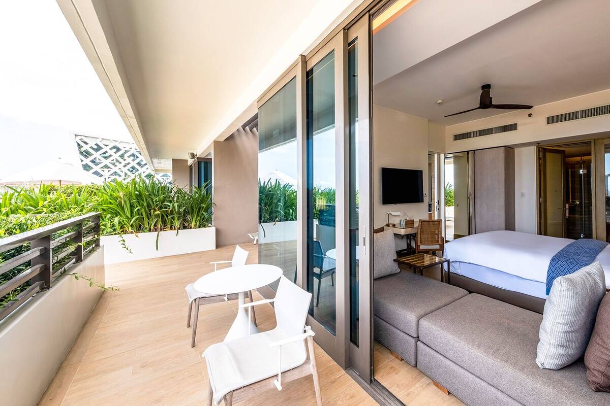 Une chambre d’hôtel moderne dotée d’un balcon, d’un lit, d’un canapé et d’une télévision.