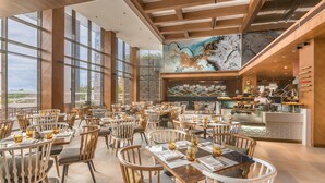 Un restaurante espacioso con techos altos, ventanas amplias y una zona de cocina central.