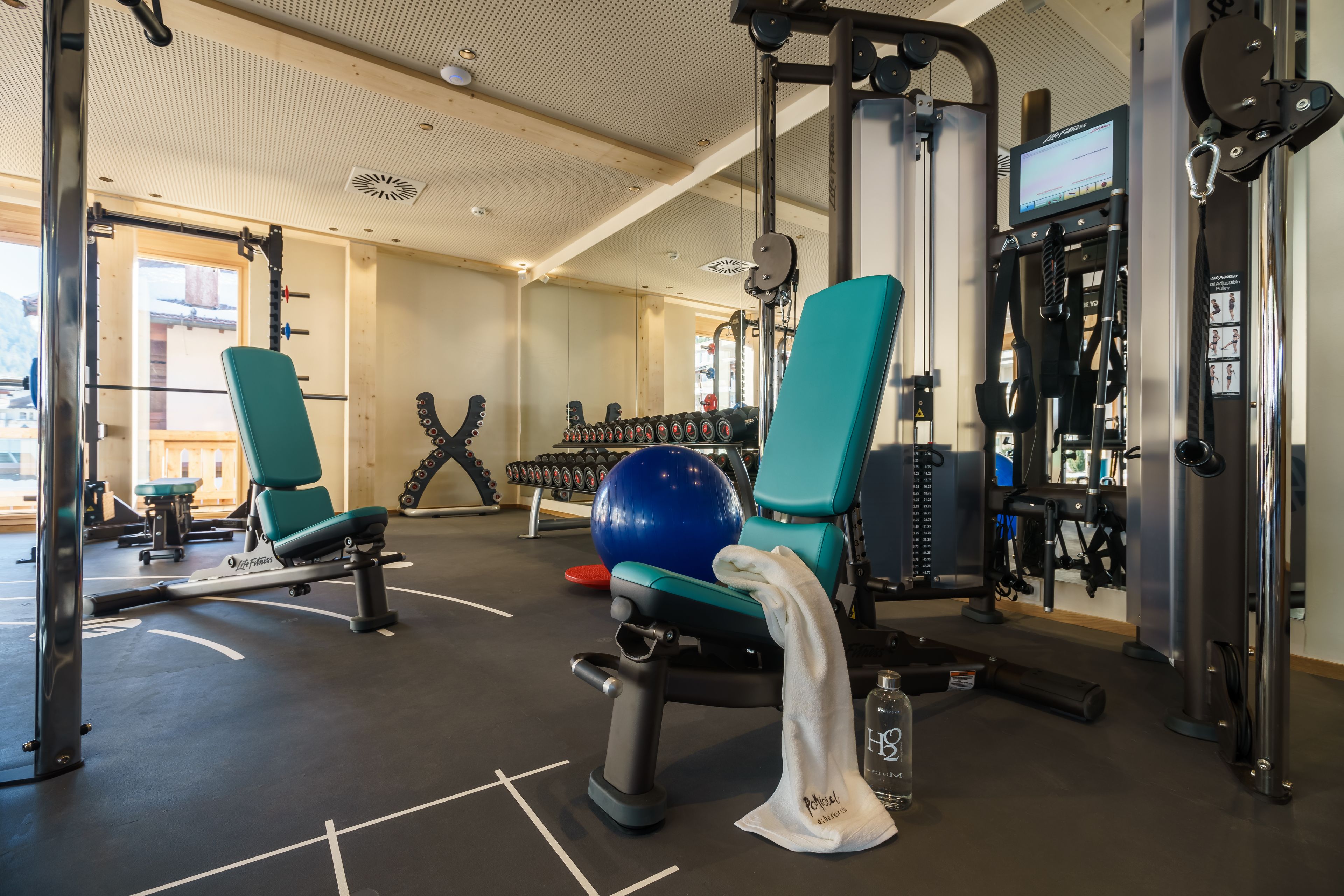 A gym with exercise equipment, a blue exercise ball, and a water bottle on the floor.