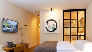 Habitación de hotel con cama, escritorio con ordenador, televisión y cuadros en la pared.