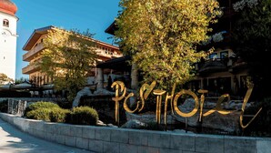 A hotel entrance with a prominent 'Posthotel' sign, a bell tower, and traditional architecture. - Posthotel Achenkirch Resort and Spa - Adults Only (Achenkirch)