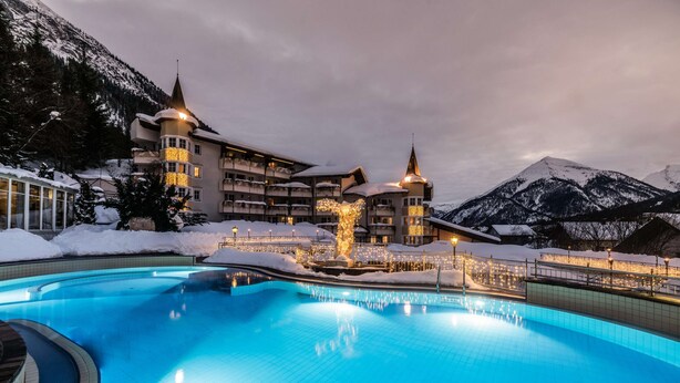 A hotel with a swimming pool, snow-covered surroundings, and mountains in the background. - Posthotel Achenkirch Resort and Spa - Adults Only (Achenkirch)
