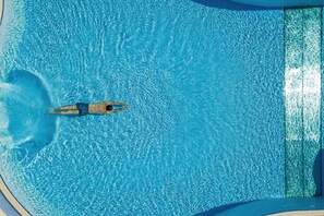 Vista aérea de una piscina con agua azul cristalina y una persona nadando.