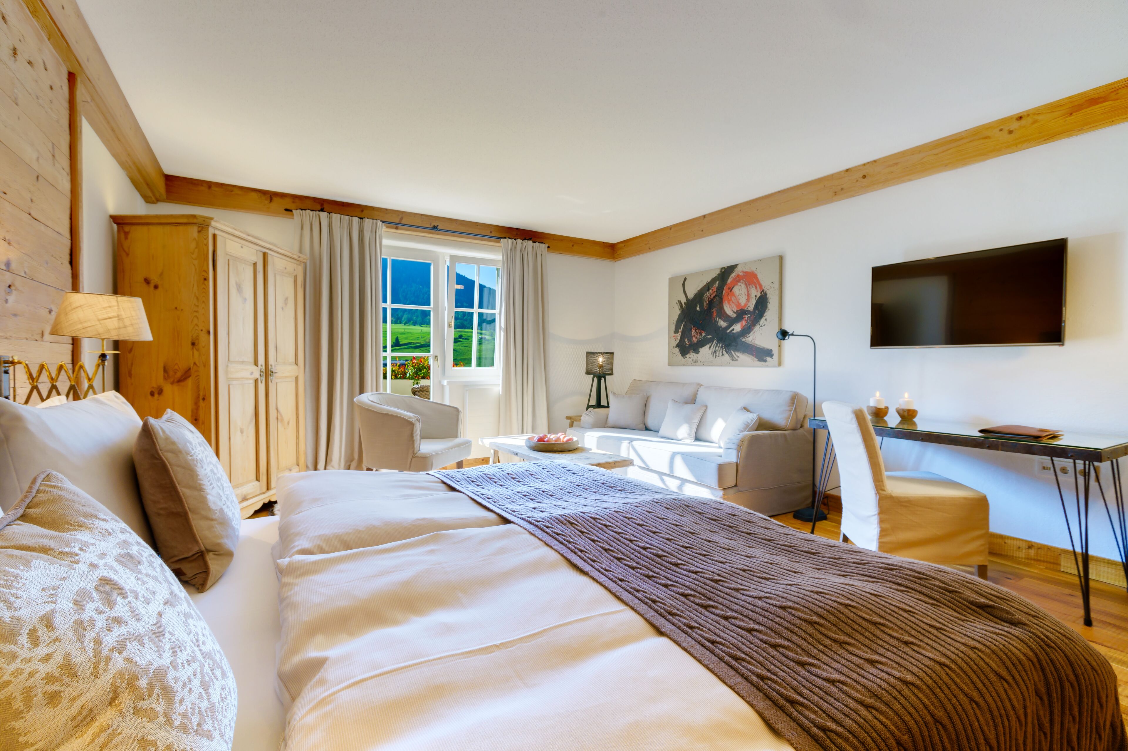 Una habitación de hotel con una cama grande, un escritorio, una silla, un sofá y un televisor.