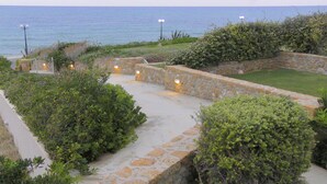 A stone pathway leading to a coastal area with a view of the sea. - Beach Front Villa Peri (Hersonissos)