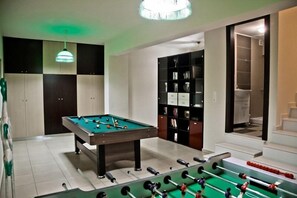 A room with a pool table, a foosball table, a bookshelf, and a staircase leading to an upper level. - Beach Front Villa Peri (Hersonissos)