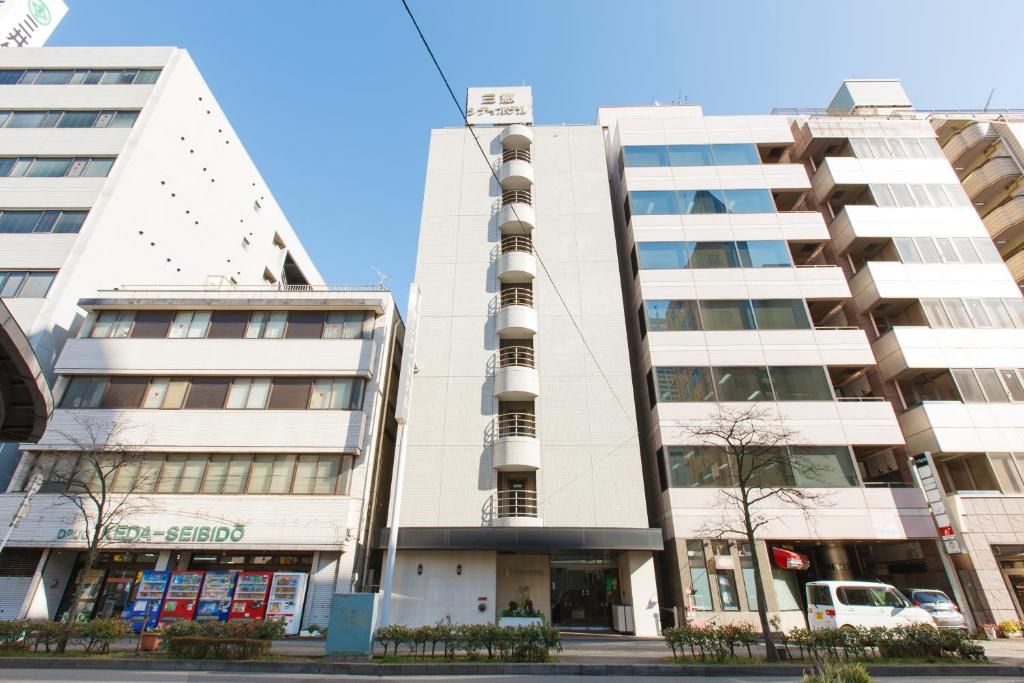 A multi-story building with a central vertical structure, a ground-level entrance, and a visible sign with Japanese characters.