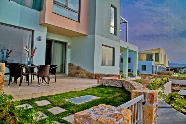 Un edificio moderno con patio, escalones de piedra y mobiliario exterior.
