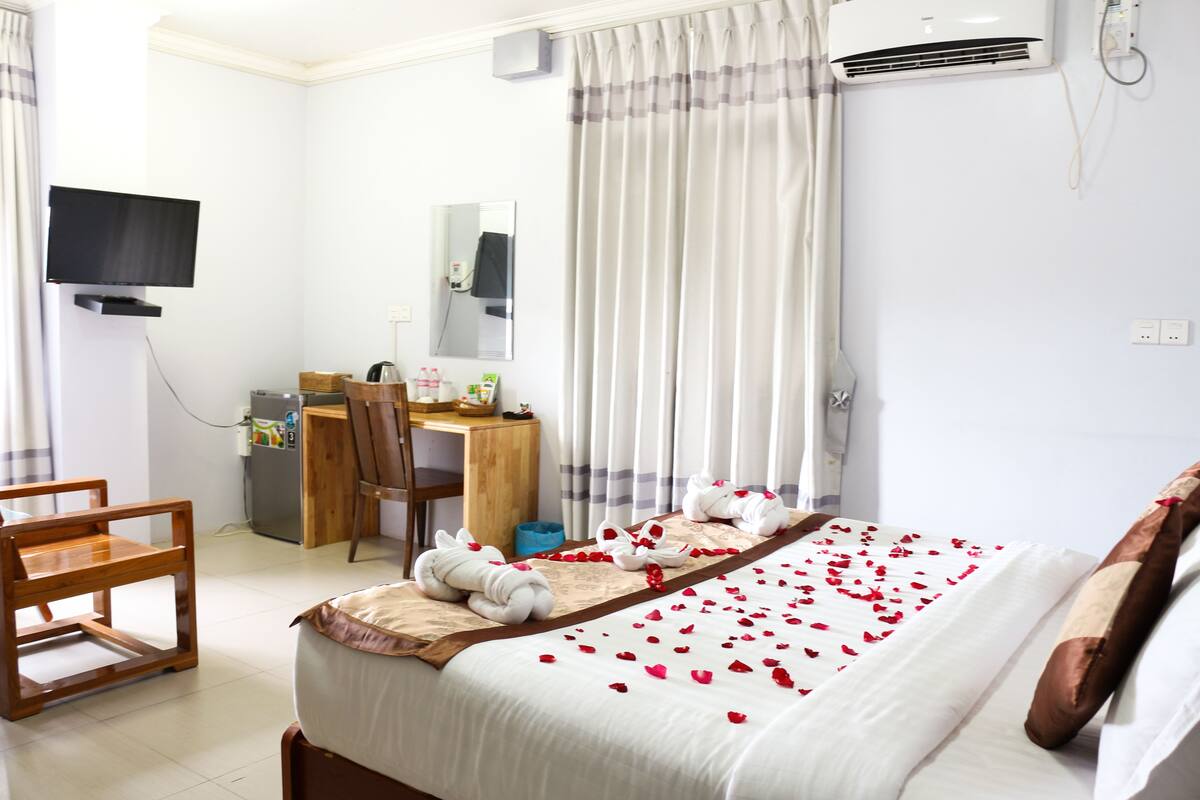 Une chambre d’hôtel équipée d’un lit, d’un bureau, d’une chaise, d’une télévision et d’un appareil de climatisation.
