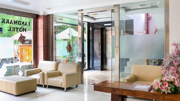A hotel lobby with a reception desk, seating area, and a glass door entrance. - Landmark Hotel (Yangon)
