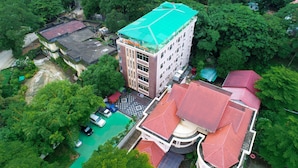 An aerial view of a hotel with a green roof, surrounded by lush greenery and other buildings. - Landmark Hotel (Yangon)