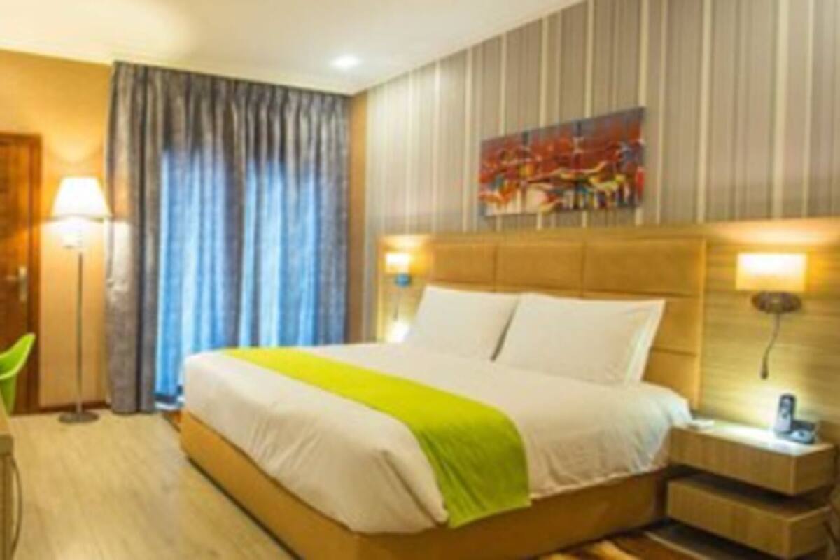 Une chambre d’hôtel équipée d’un lit, d’une table de chevet, d’une lampe et d’un téléviseur.