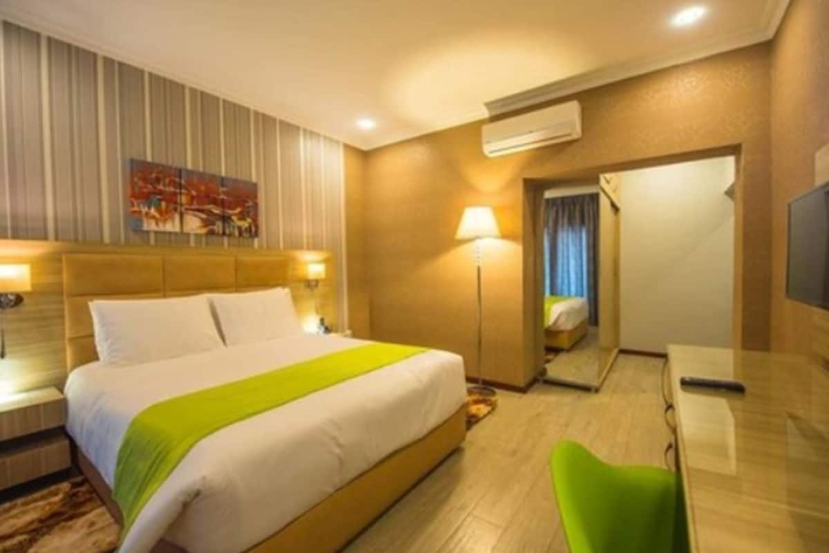 Une chambre d’hôtel avec un lit, une table de chevet, une lampe et un téléviseur.