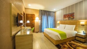 Ein Hotelzimmer mit Bett, Nachttischen, Schreibtisch, Fernseher und einem Gemälde an der Wand.