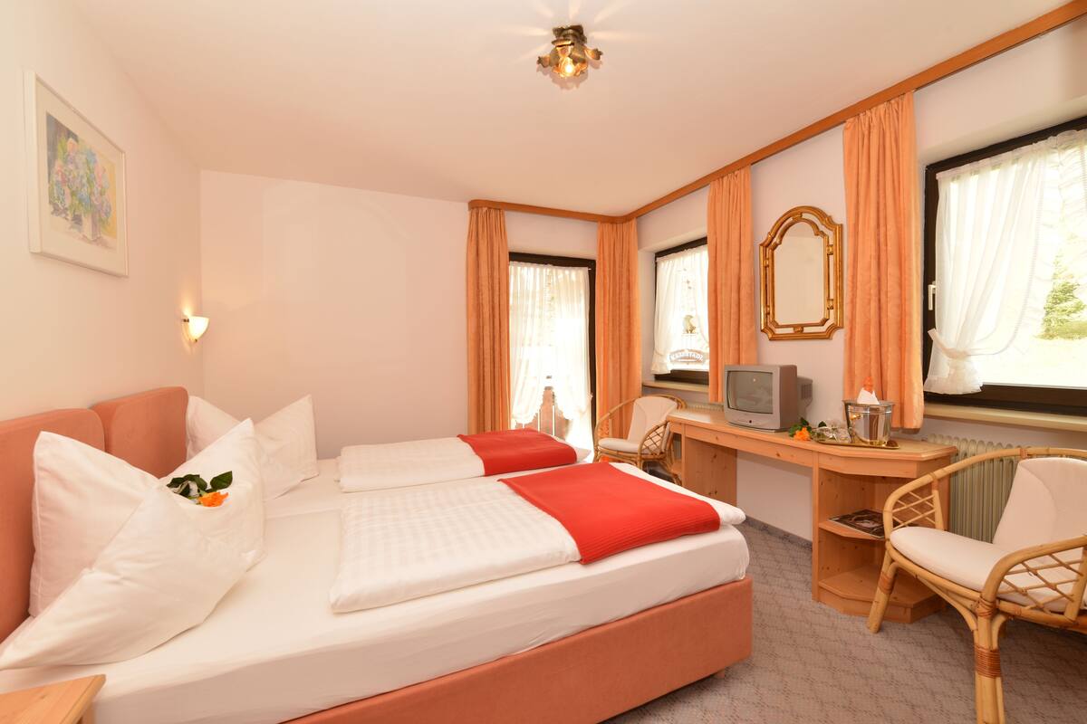 A hotel room with a large bed, a desk with a television, and a chair.