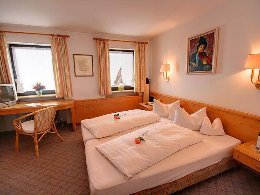 Una camera d'albergo con due letti, una scrivania, una sedia, una televisione e un quadro appeso al muro.