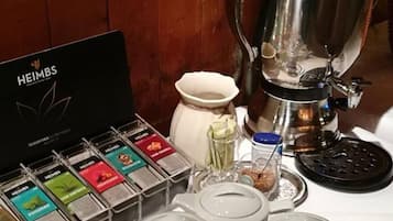 A coffee station with a coffee maker, tea bags, and teapots.