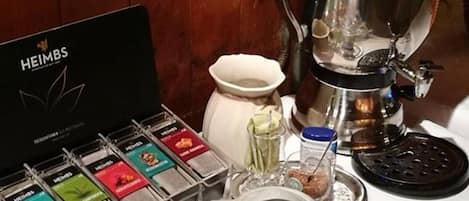A coffee station with a coffee maker, tea bags, and teapots.