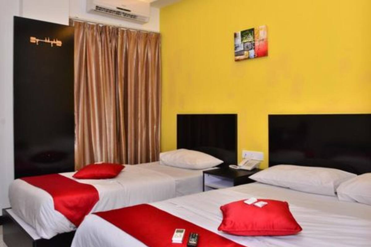 Ein Hotelzimmer mit zwei Betten, einer gelben Wand und einem schwarzen Kopfteil.