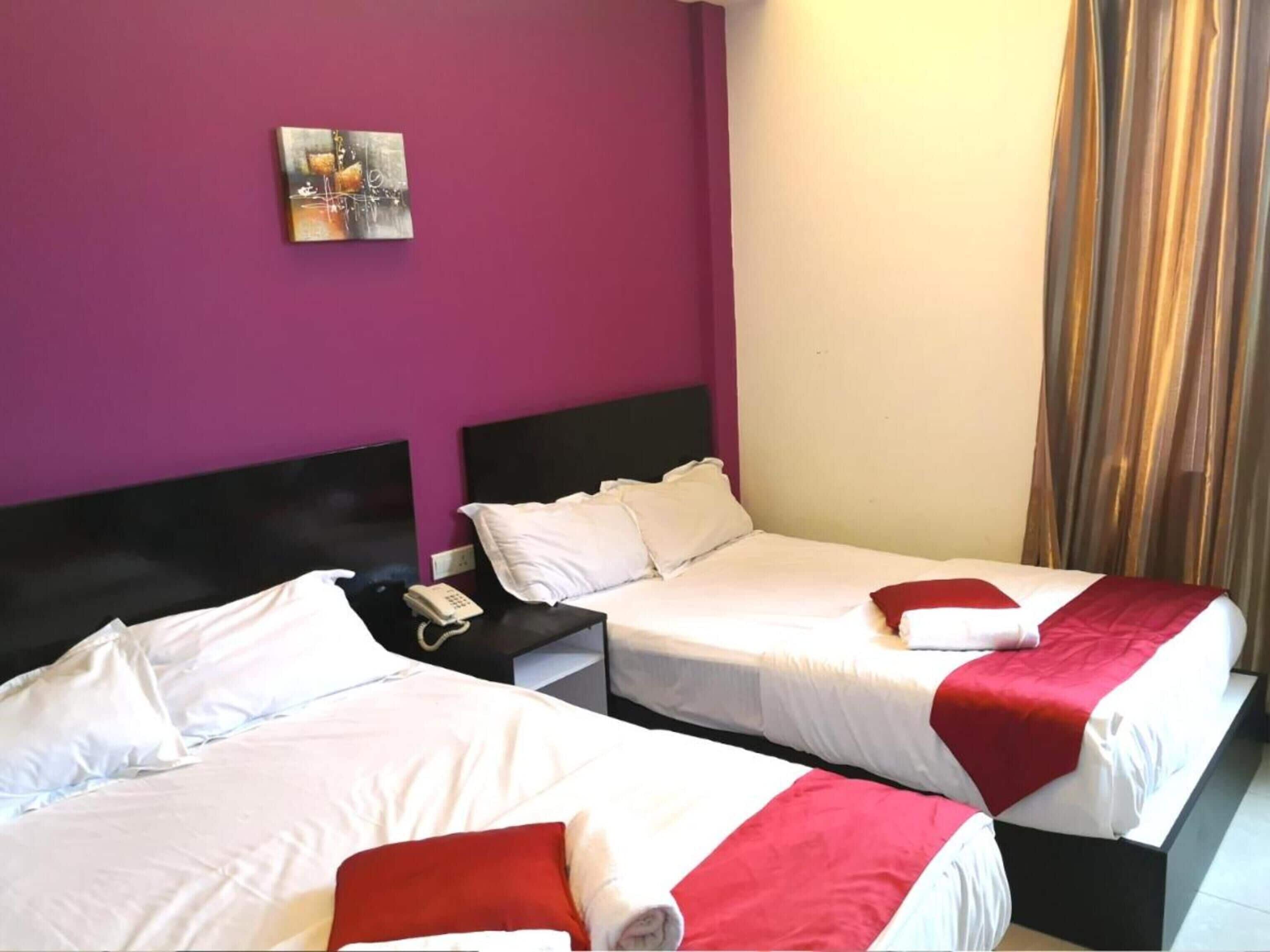 Una habitación de hotel con dos camas, una mesita de noche con un teléfono y un cuadro en la pared.
