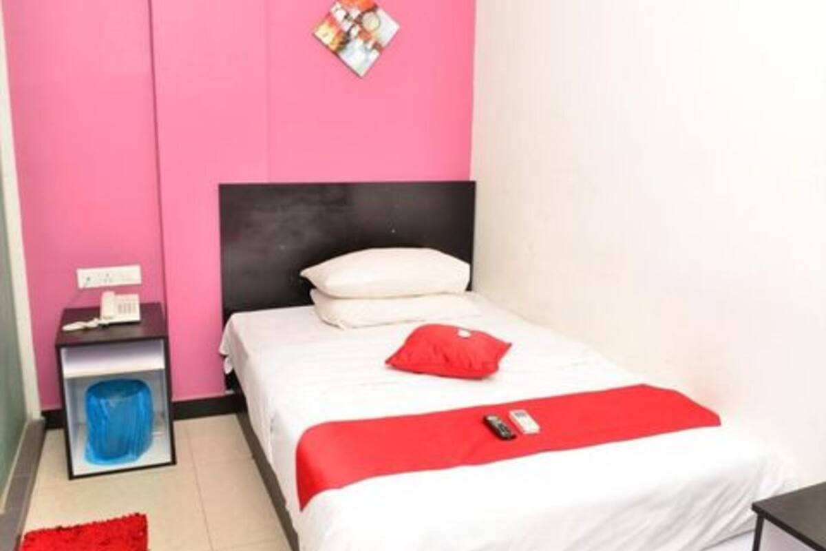 Ein Schlafzimmer mit einem Bett, einem Nachttisch, einem roten Teppich und einer Wanduhr.