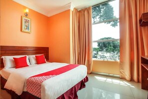 A hotel room with a large bed, a window with curtains, a wooden headboard, and a wall-mounted light fixture. - 89470 My Town Hotel (Ipoh)