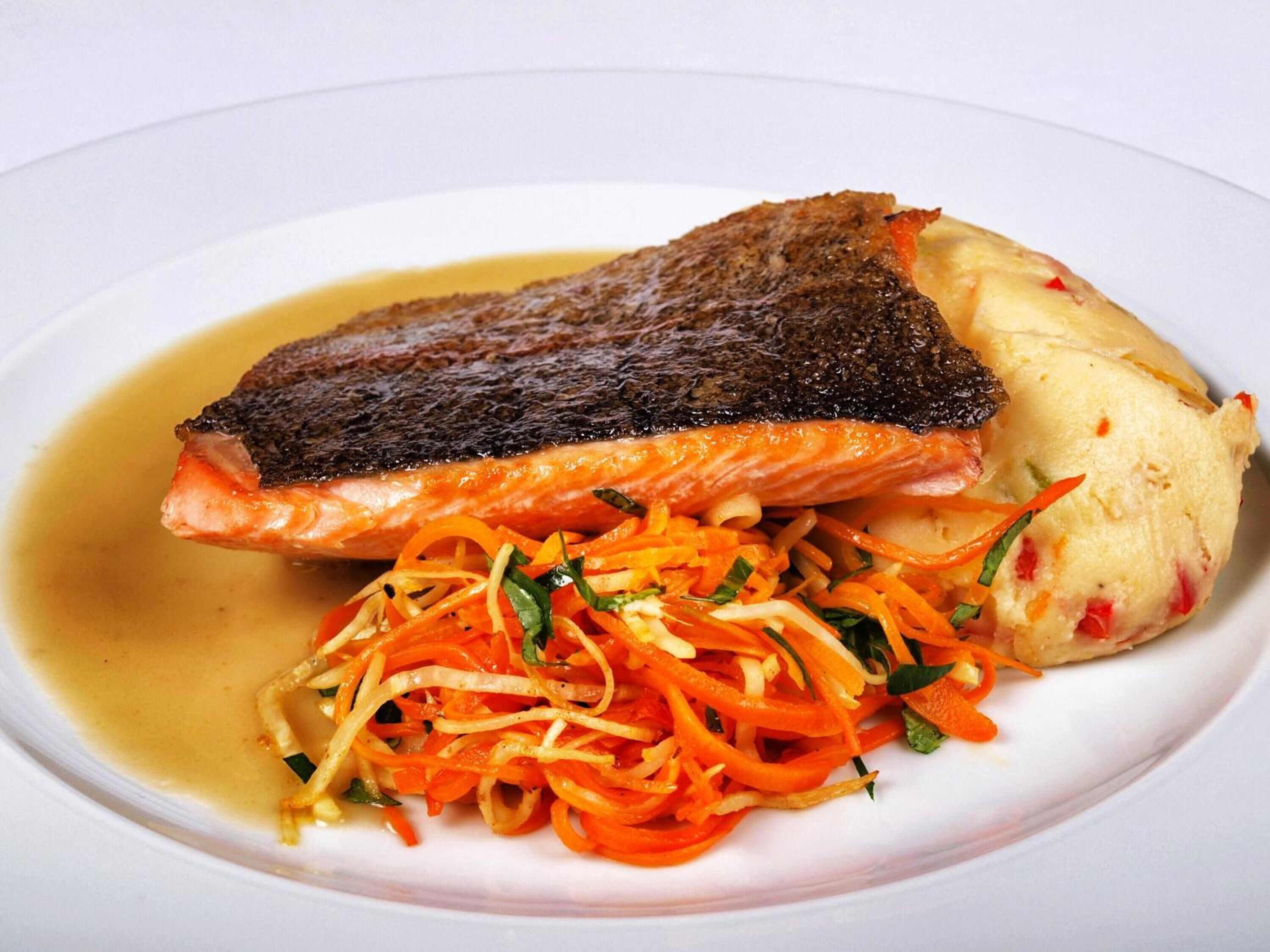 A plate with a piece of salmon, a carrot salad, and a scoop of ice cream.