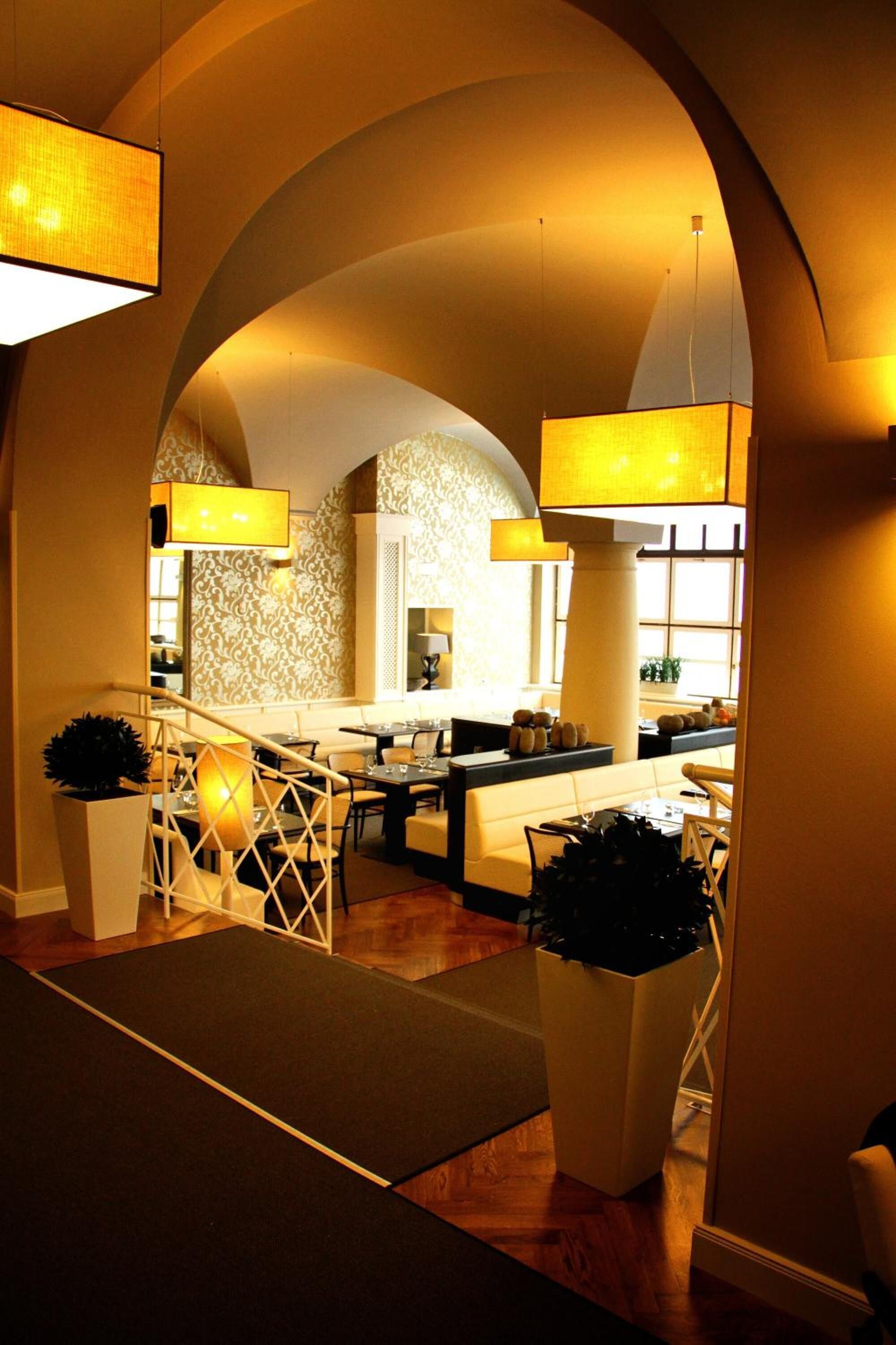 Un interior moderno con zona de comedor central, una escalera y vistas a través de un arco.