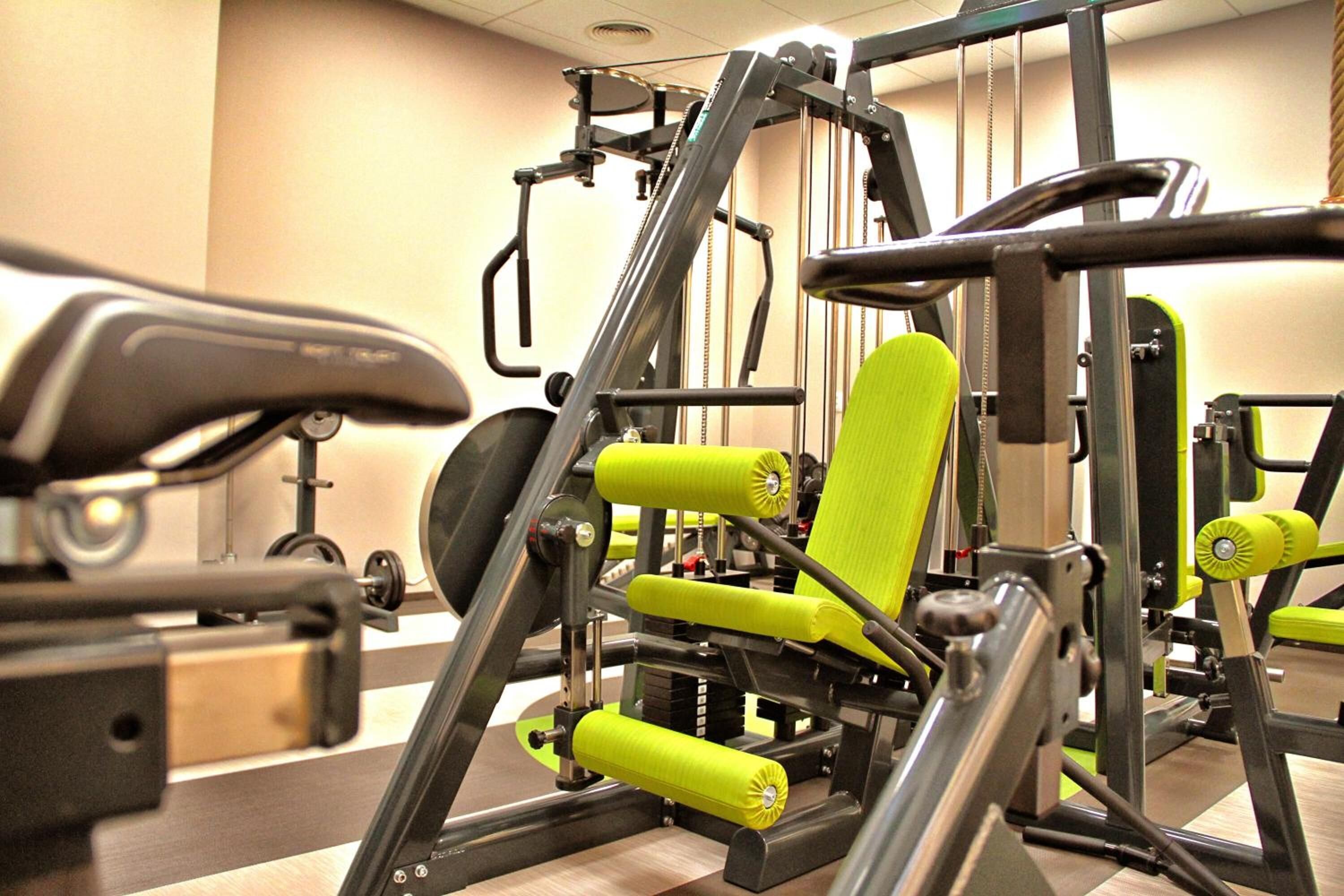 Ein Fitnessraum mit Trainingsgeräten, darunter eine Bank und Gewichtsmaschinen.