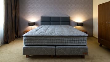 A bed with a quilted mattress, two bedside lamps, and a wooden wardrobe.