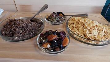 A buffet table with four glass bowls containing different types of food.
