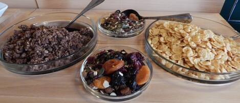 Una mesa de buffet con cuatro recipientes de vidrio que contienen diferentes tipos de comida.