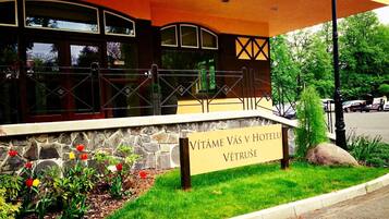 Entrada de un hotel con un muro de piedra y un letrero que dice "VITÁME VÁS V HOTELU VETRUŠE".