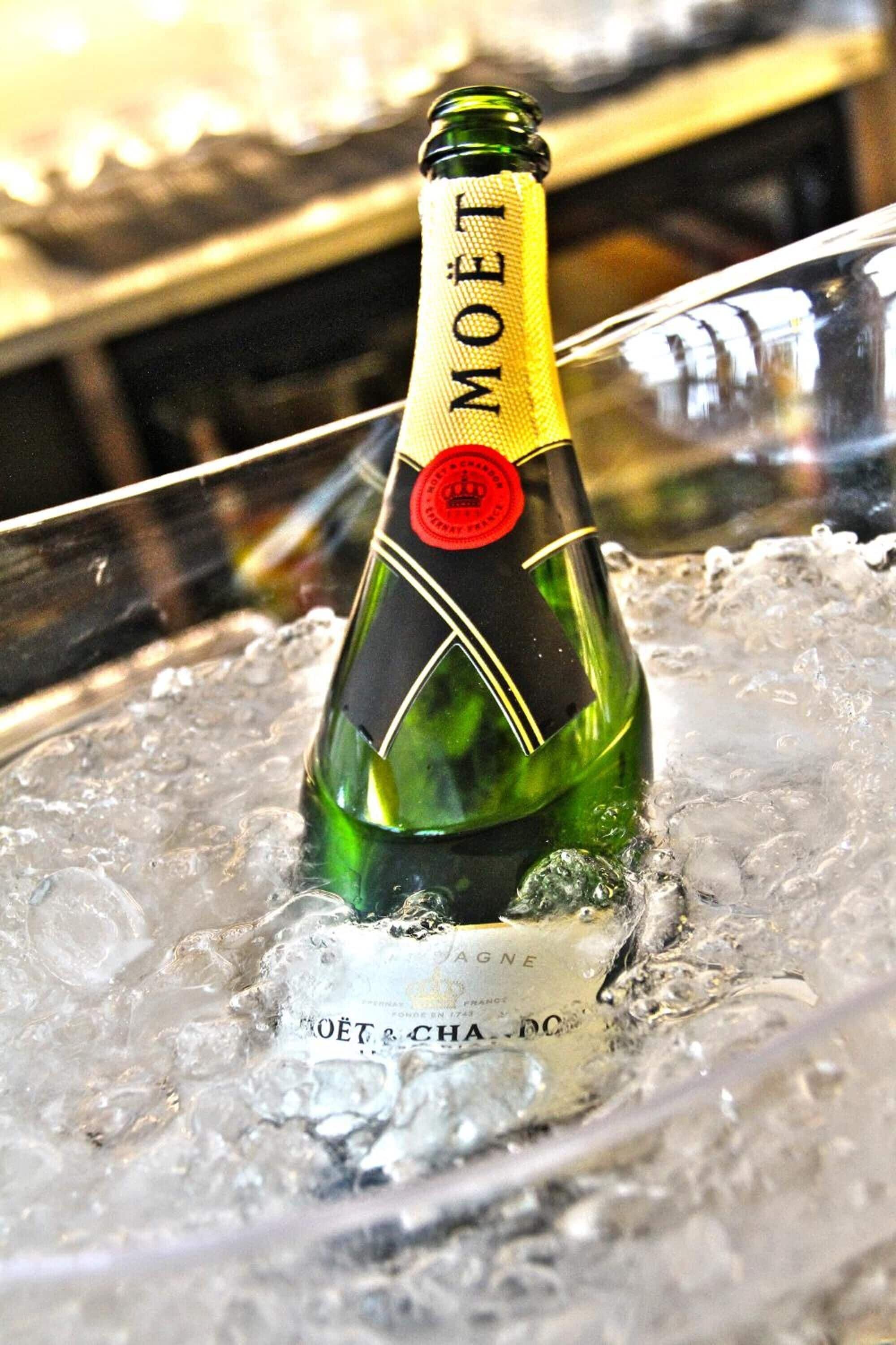 Une bouteille de champagne Moët dans un verre rempli de glaçons.